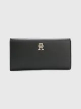 Billetera grande de Tommy Hilfiger en color negro con textura granulada, cierre de botón a presión y monograma TH metálico en tono dorado en la parte frontal.