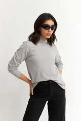 Sweater gris de tejido de punto fino, con cuello alto y mangas largas.