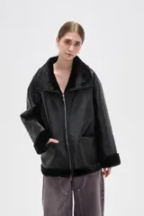 Campera de cuero sintético con interior y detalles de piel sintética en cuello, puños y ruedo. Presenta cierre frontal completo y diseño de corte holgado.