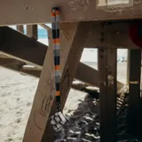 Llavero para colgar al cuello con cinta estampada con bloques geométricos en tonos azul, naranja y blanco. Incluye mosquetón metálico negro y aplique de cuero sintético negro.