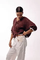 Saco de punto gris con frente abierto y cierre mediante lazos frontales. Presenta mangas abullonadas con puños elásticos y un diseño de textura voluminosa.