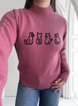 Sweater fucsia de punto con cuello alto y estampado de siluetas de gatos en el frente.