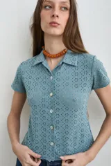 Camisa de broderie color celeste, con cuello camisero, manga corta y cierre frontal con botones de nácar.