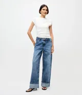 Pantalón wide leg de tiro bajo confeccionado en denim de algodón. Presenta un diseño de pierna amplia con ruedo doblado, cintura con pasadores y cierre frontal con botón y cremallera.