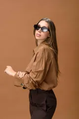 Camisa color habano de corte clásico, con cuello camisero, bolsillos frontales con solapa y puños anchos con detalle de botón metálico.