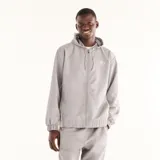 Campera New Balance de hombre, modelo Trackside, de color gris. Presenta capucha con cordón ajustable, cierre frontal completo y el logo de la marca estampado en el pecho.