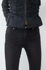 Blusa blanca de manga larga con escote redondo, cierre frontal oculto y detalles de frunces laterales en el cuerpo.