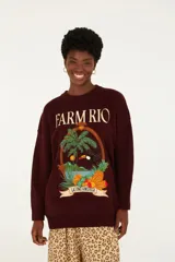 Sweater de punto oversized bordó con cuello redondo y mangas largas con terminaciones acanaladas. Presenta un estampado frontal de estilo tropical con el texto 'Farm Rio' y 'Latino America', acompañado de ilustraciones de una palmera, un tucán y frutas.