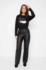 Pantalón de corte recto confeccionado en cuero sintético negro, con cierre frontal, botón y bolsillos laterales.