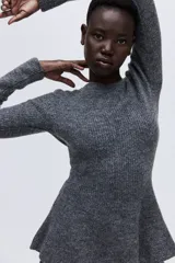 Buzo de punto acanalado en color gris, con escote bote, manga larga y diseño entallado con detalle de peplum en la cintura.