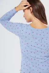 Remera de manga larga con cuello redondo, confeccionada en tejido suave con estampado de pequeñas hojas en tonos azul y rojo sobre fondo celeste.