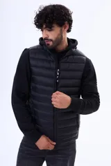 Chaleco acolchado negro con cierre frontal completo y cuello alto. Diseño ligero y sin mangas, ideal para superponer capas.