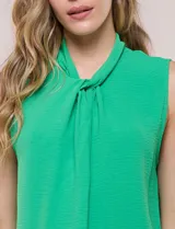 Blusa sin mangas color verde, confeccionada en crepé texturizado, con cuello alto drapeado y torsión central frontal.
