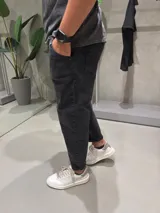 Jean de corte slouchy en color negro con efecto gastado. Presenta un diseño de tiro medio, ajuste holgado en la cadera y piernas que se estrechan hacia el tobillo.