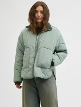 Campera puffer color verde menta, con diseño matelaseado de ondas, cuello alto tejido en tono verde oscuro, cierre frontal y amplios bolsillos frontales aplicados.