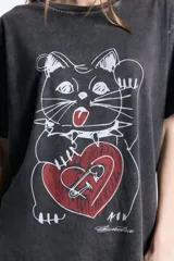 Remera de jersey de algodón con efecto lavado, corte oversize, cuello redondo y manga corta. Presenta un estampado frontal de un gato con un corazón rojo.
