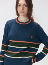 Sweater de punto cable con diseño a rayas horizontales en tonos marrón, amarillo y lila. Presenta cuello redondo acanalado, mangas largas con puños a juego y logo bordado en el pecho.