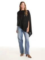 Poncho tejido de punto con diseño asimétrico y aberturas laterales para los brazos.