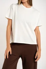 Remera blanca de algodón peinado, corte al cuerpo, con cuello redondo y mangas cortas. Presenta un detalle de costura vertical en la zona del hombro/manga.