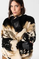 Buzo de peluche con estampado de paisaje montañoso en tonos beige, negro y blanco. Presenta cuello alto con cierre frontal, mangas largas con puños tejidos acanalados y corte holgado.