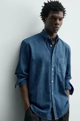 Camisa regular fit de denim de algodón azul, con cuello solapa, manga larga con puños abotonados, un bolsillo de parche en el pecho y cierre frontal de botonadura.