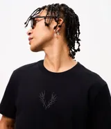 Remera masculina de algodón negro con cuello redondo, mangas cortas y corte comfort. Presenta un estampado tribal sutil en el centro del pecho.