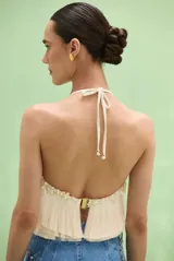 Top halter color marfil con escote redondo, espalda descubierta y diseño de capas de flecos con apliques de perlas y cuentas en el cuello.