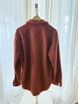 Camisa campera oversize de corderito color tostado con interior forrado en tela estampada, bolsillos frontales con solapa y cierre de botones.