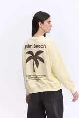 Buzo de algodón color lila, de calce relajado y hombros caídos, con estampa pequeña en el frente que dice "Palm Beach" y una palmera.