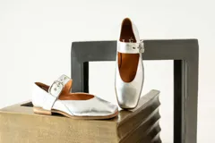 Zapato bajo de gamuza color beige con correa sobre el empeine y hebilla dorada.