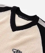 Suéter de punto con corte boxy, diseño bicolor en crema y negro. Presenta cuello en V, mangas largas con rayas laterales y estampa frontal con lettering Untitled y detalles gráficos. Cuenta con terminaciones acanaladas a rayas en el ruedo y puños.