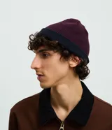 Gorro de punto con doblez, diseño reversible bicolor en tonos azul marino y bordó, confeccionado en lana acrílica.