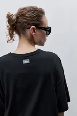 Remera negra de silueta amplia y calce relajado, con cuello redondo, mangas cortas con hombros caídos y estampa botánica en líneas blancas en el frente.
