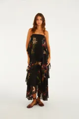 Vestido largo negro con tirantes finos, escote recto y diseño escalonado con capas superpuestas de volados con estampado floral.