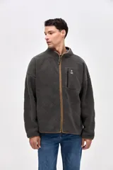 Campera de sherpa con diseño capitoneado en color crema. Presenta cierre frontal completo, cuello alto, bolsillos laterales y un bolsillo en el pecho con cierre en contraste. Incluye detalles en nylon y bordado decorativo en el pecho.