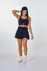 Conjunto deportivo compuesto por un top de escote redondo con logo estampado y una pollera short con diseño plisado y cintura alta.