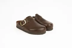 Zueco de gamuza color marrón con tira ajustable mediante hebilla metálica dorada, suela de corcho y base de goma estriada.