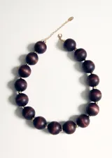 Collar de cuentas esféricas de madera en tonos marrones oscuros, separadas por pequeños abalorios metálicos dorados.