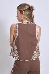 Blusa negra sin mangas, de corte recto y escote redondo, con detalles de bordados contrastantes en color blanco en los bordes y costados.