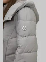 Campera puffer color gris, con cuello alto y capucha desmontable. Cierre frontal con cremallera y bolsillos laterales con cierre. Diseño acolchado y detalles distintivos de Calvin Klein.