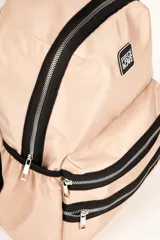 Mochila de diseño funcional en color verde militar, confeccionada en material sintético resistente. Cuenta con un compartimento principal con cierre, dos bolsillos frontales con cierres metálicos visibles, y bolsillos laterales. Incluye asas traseras regulables y una manija superior fija. Presenta un parche con el logo de la marca en la parte frontal.