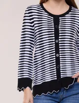 Cardigan de silueta recta confeccionado a rayas horizontales en contraste de negro y blanco, con detalles de calados sutiles y terminaciones onduladas. Cuenta con escote redondo clásico, cartera frontal completa con botones a tono, y mangas largas finalizadas en puños anchos con borde ondulado.