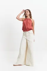 Blusa sin mangas color terracota, con cuello halter fruncido y elástico en la cintura. Presenta un diseño holgado y fresco con acabado tipo lino.