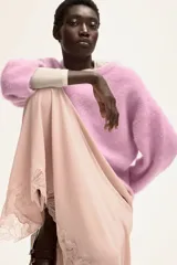 Buzo de punto rosa claro, con textura suave y peluda, cuello redondo y mangas largas de corte caído.