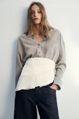 Camisa fluida de corte oversize confeccionada en mezcla de viscosa, con diseño de rayas verticales finas en tono beige sobre fondo blanco. Presenta cuello solapa, cierre frontal con botones, manga larga con puños y un bolsillo de plastrón en el pecho.