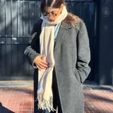 Bufanda de lana color beige con flecos en los extremos.