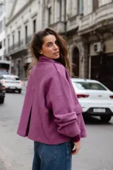 Chaqueta de lana afieltrada en color amarillo mostaza, con cuello camisero, cierre frontal con broches a presión y bolsillos delanteros. Presenta un diseño de espalda con apertura para mayor movimiento.