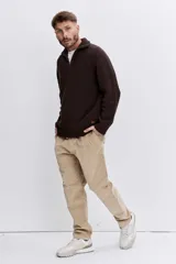 Sweater de punto acanalado en color marrón oscuro, con cuello alto y cierre frontal de cremallera parcial. Presenta mangas largas y puños ajustados.