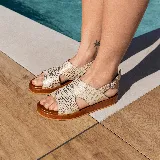 Sandalias de cuero color blanco con textura tipo reptil, plataforma marrón y hebilla metálica plateada.