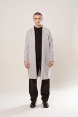 Sacón largo de corte recto y diseño abierto, confeccionado en tela simil paño color gris melange. Presenta mangas largas con terminaciones al corte, bolsillos ocultos y ruedo recto.